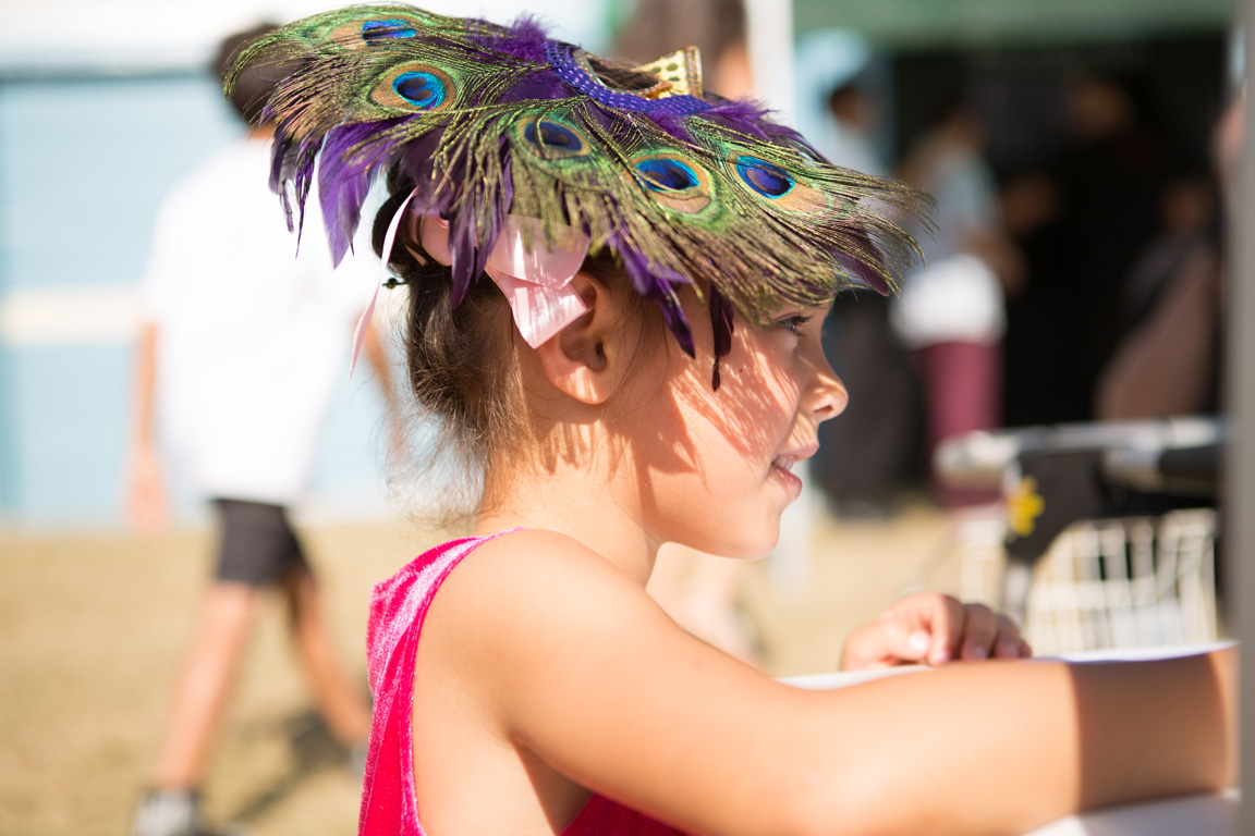 A child wearing a colourful peacock-feather headpiece at a community event